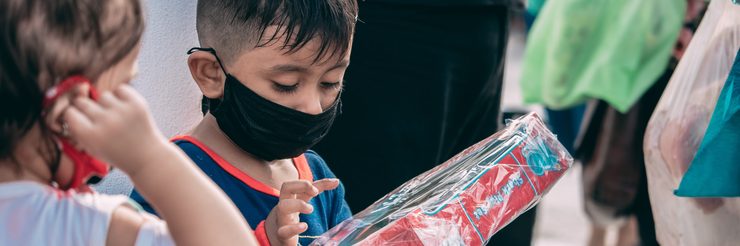 Two small children, both wearing masks, receiving and admiring a gift from a charity toy drive. Header for "How Giving Tuesday Can Impact Nonprofit Branding."