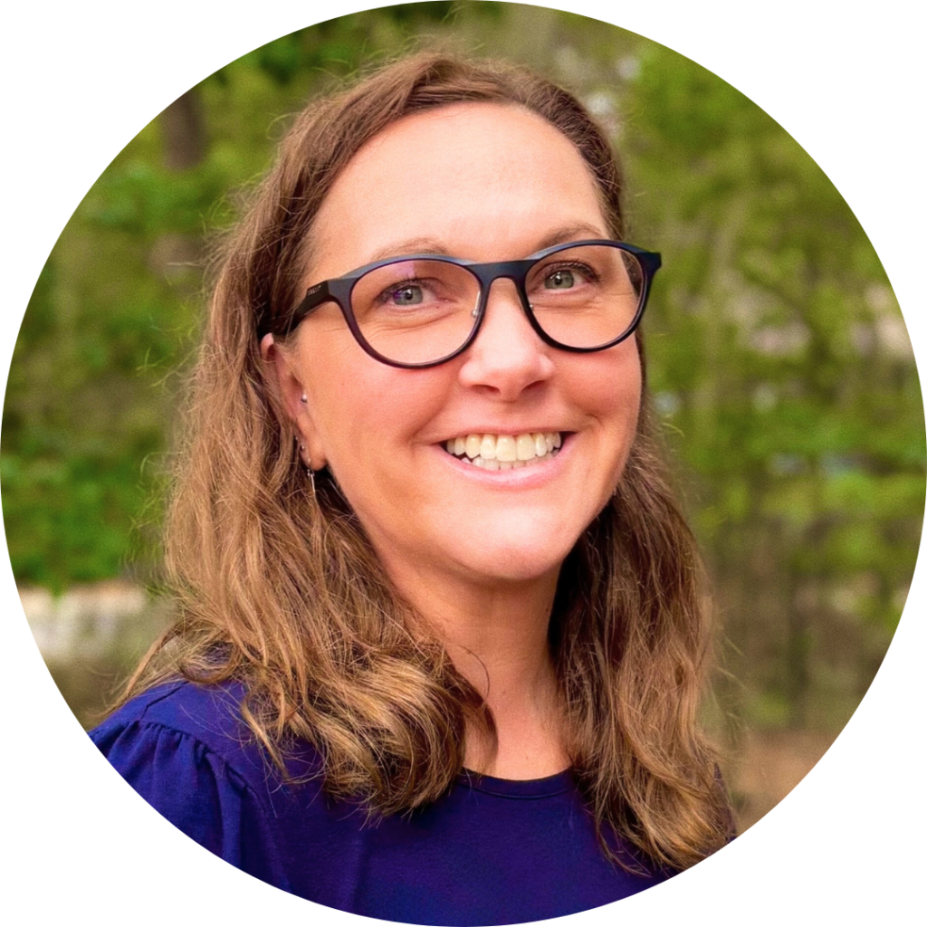 A woman (Laura Pierce, Operations Manager) smiling. She has light brown, shoulder-length hair, glasses, and a navy blue blouse.